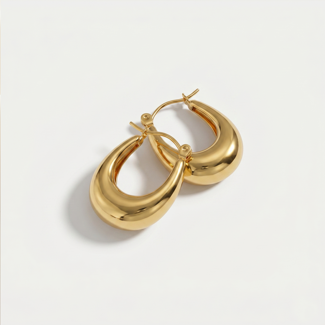 A pair of chunky gold-plated dome hoop earrings on a plain background