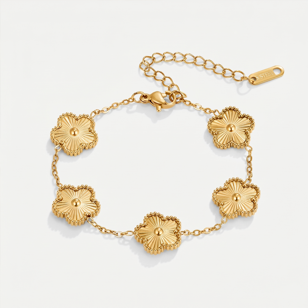A gold-tone chain bracelet with five textured clover flowers, on a plain background