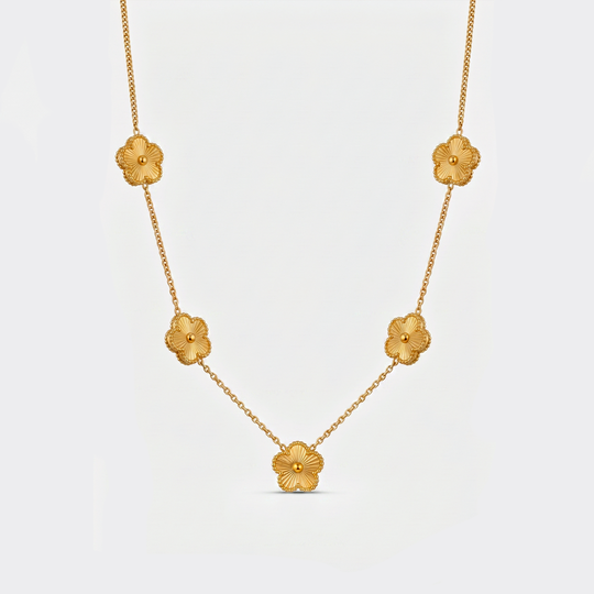 A gold-tone chain necklace with five textured clover flowers, on a plain background