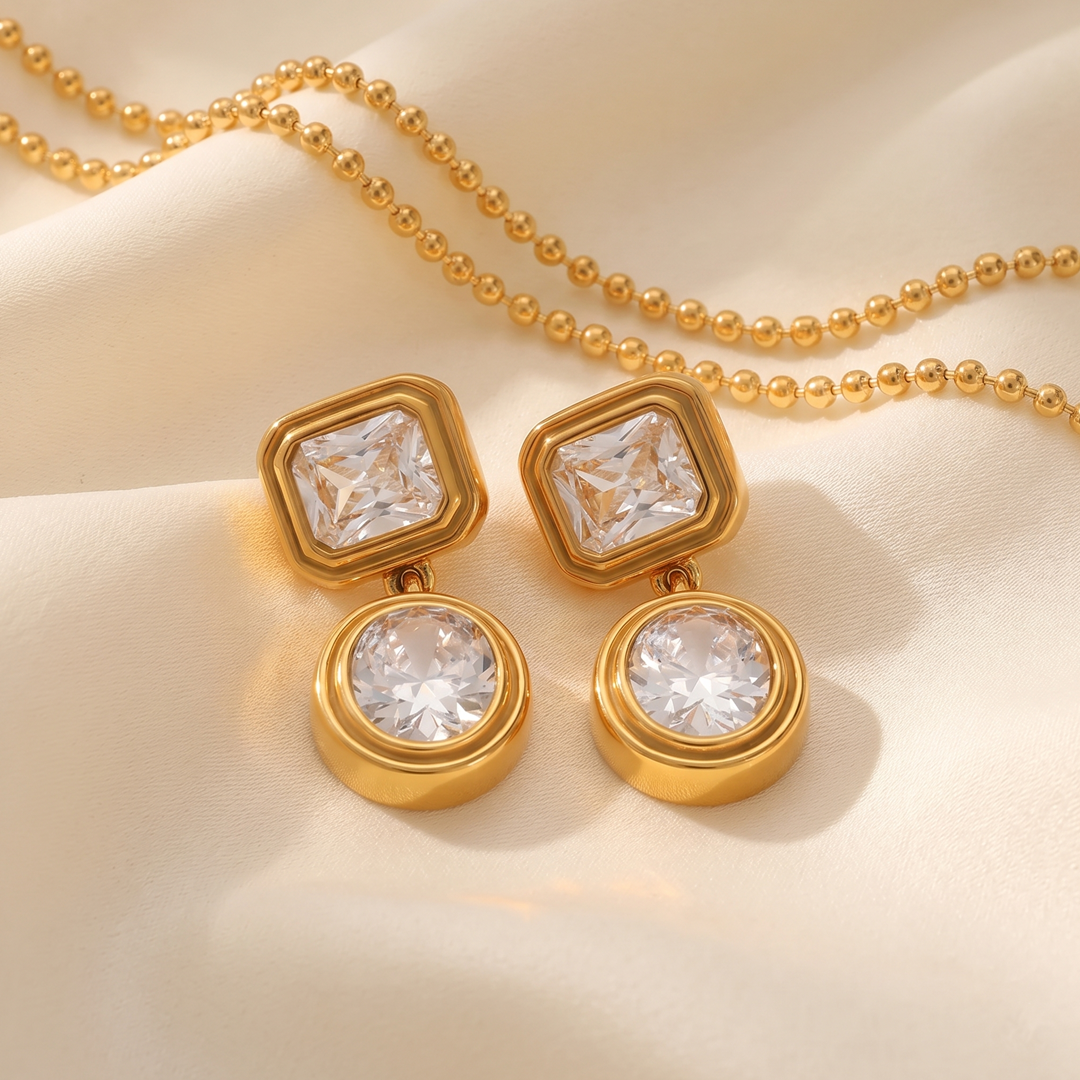 The crystal drop earrings resting on cream silk