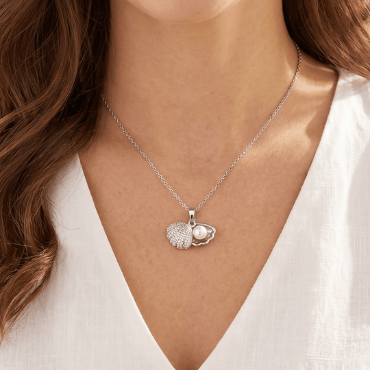 The shell pendant in silver-tone worn, sitting just below the collarbone