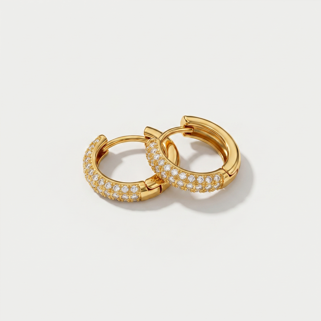 A pair of gold-tone huggie hoop earrings with a row of cubic zirconia along the front