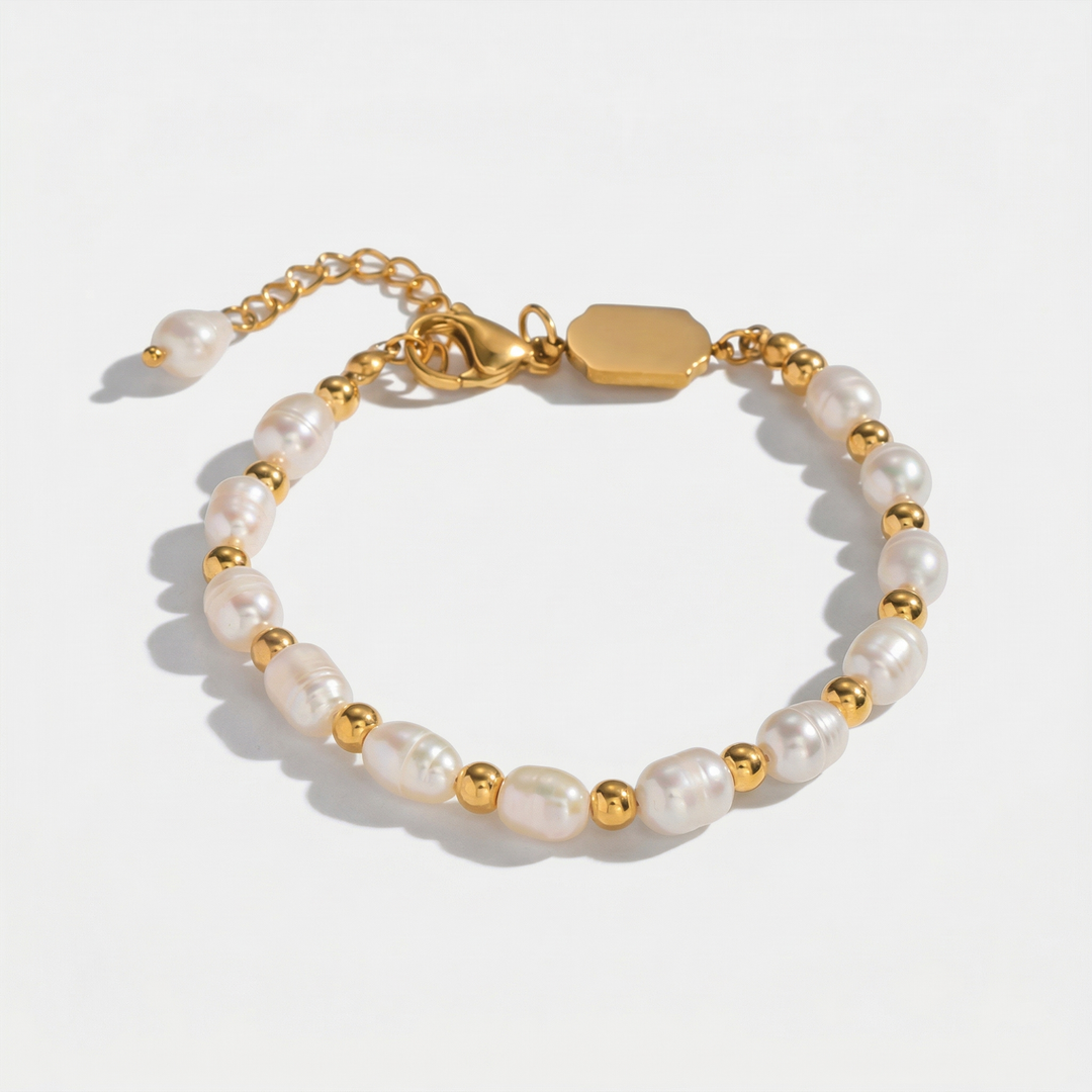 A bracelet of oval freshwater pearls and small gold-tone beads, on a plain background
