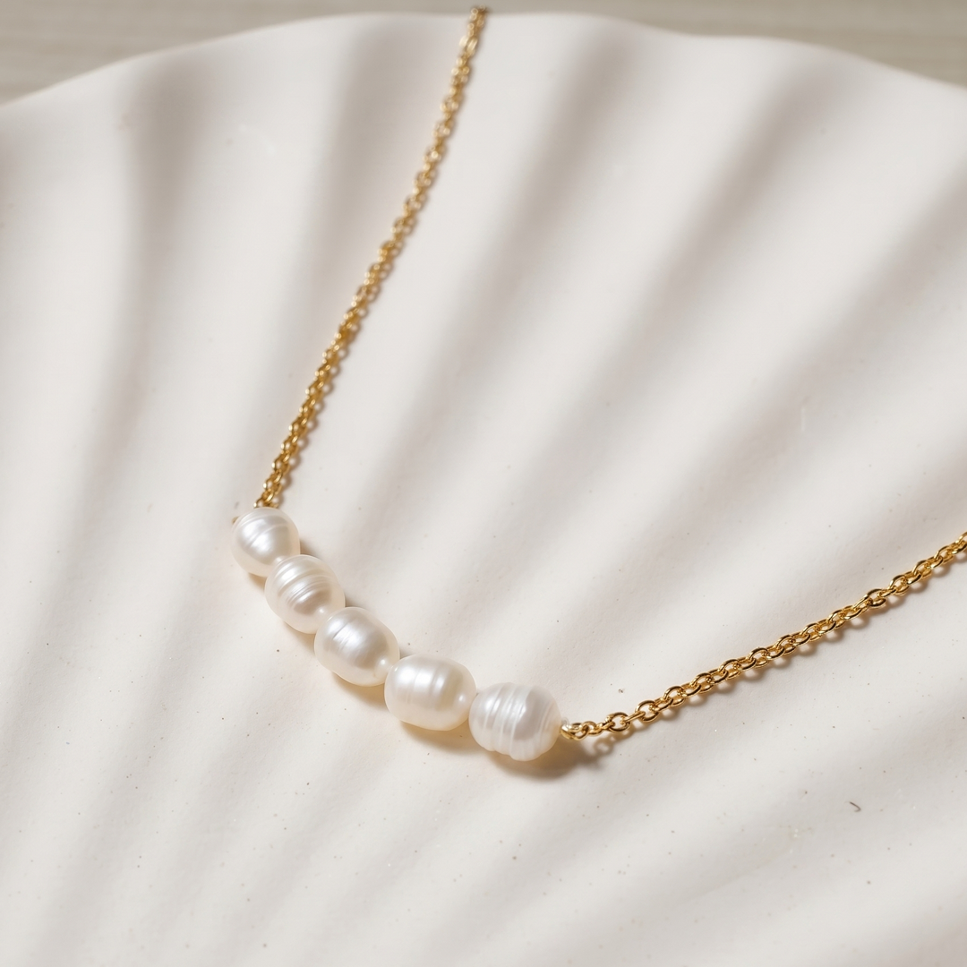 Close detail of the six pearls on the fine gold-tone chain