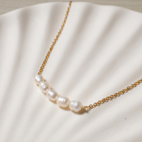 Close detail of the six pearls on the fine gold-tone chain