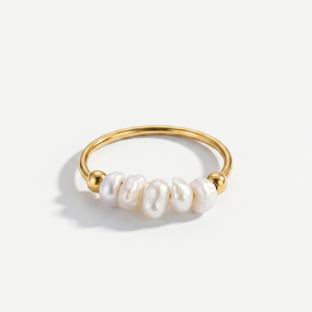 A fine gold-plated ring with four freshwater pearls, on a plain background