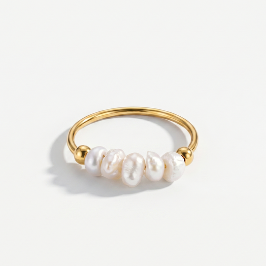 A fine gold-plated ring with four freshwater pearls, on a plain background