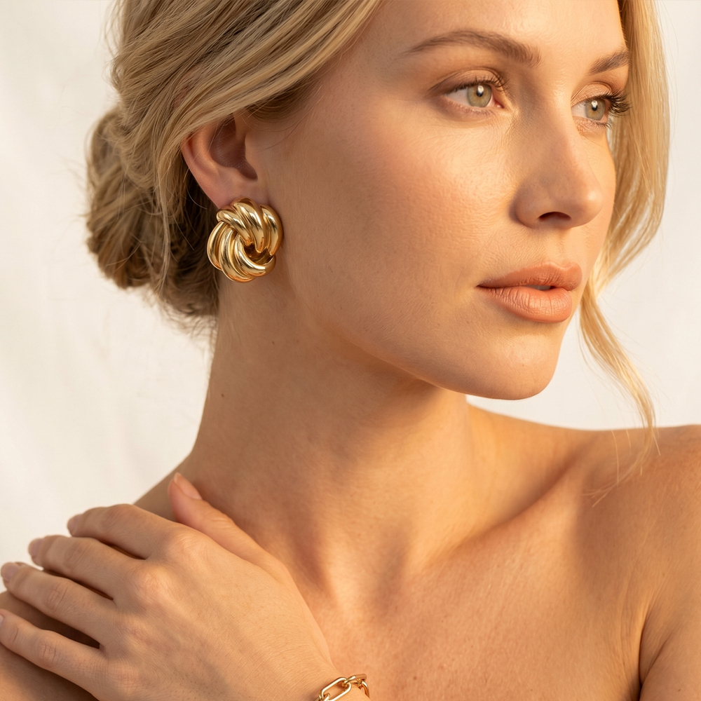 A gold-tone swirl stud worn, showing how the round stud sits flat on the lobe