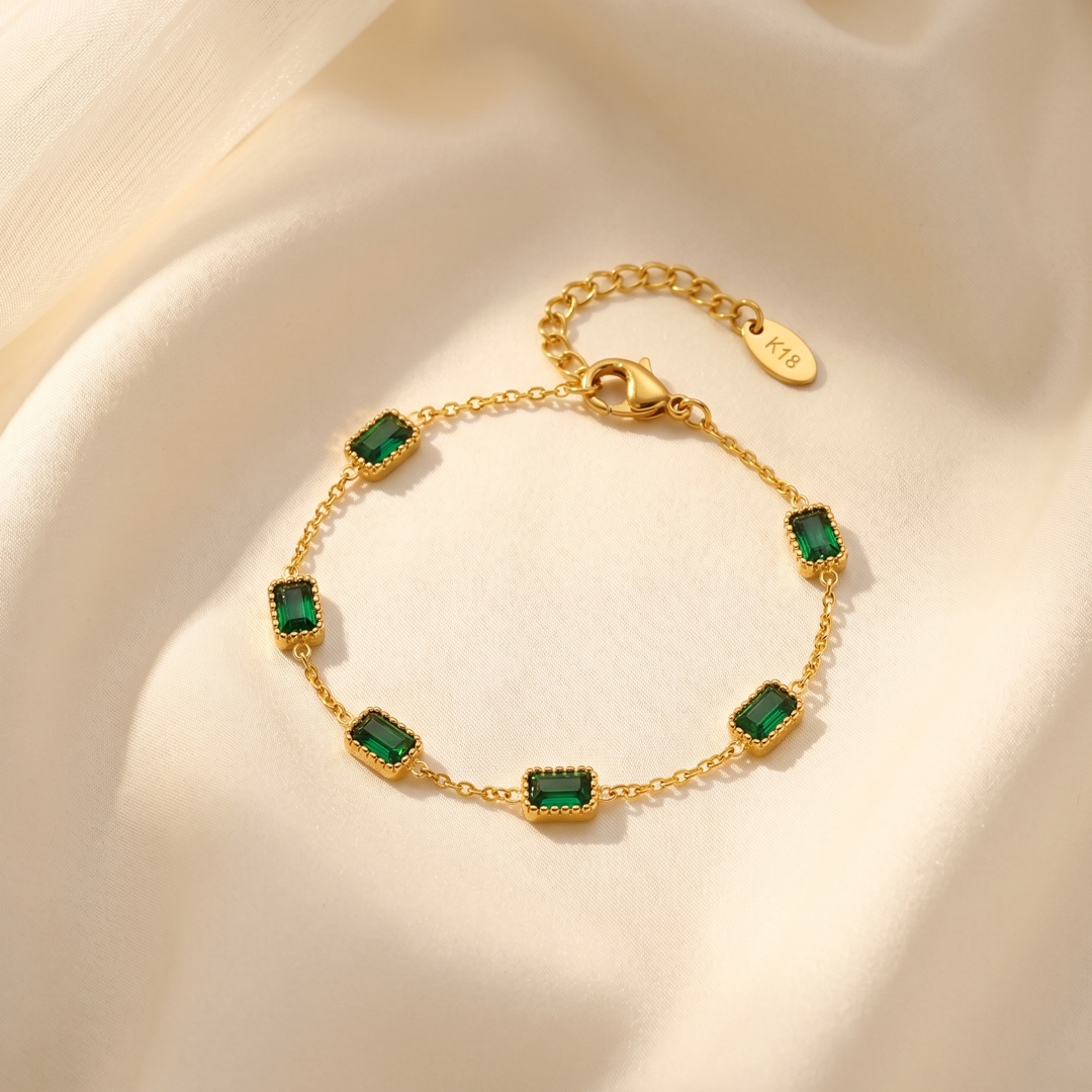 The green crystal bracelet resting on cream silk, showing the clasp and extension