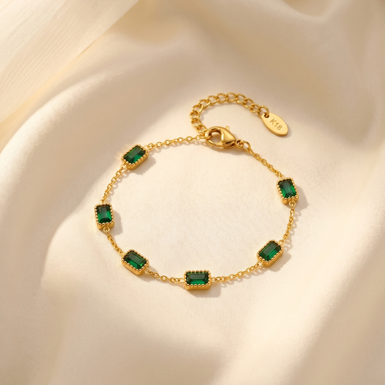 The green crystal bracelet resting on cream silk, showing the clasp and extension