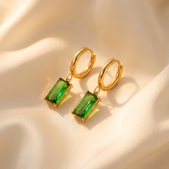 The pair of green crystal hoops resting on cream silk