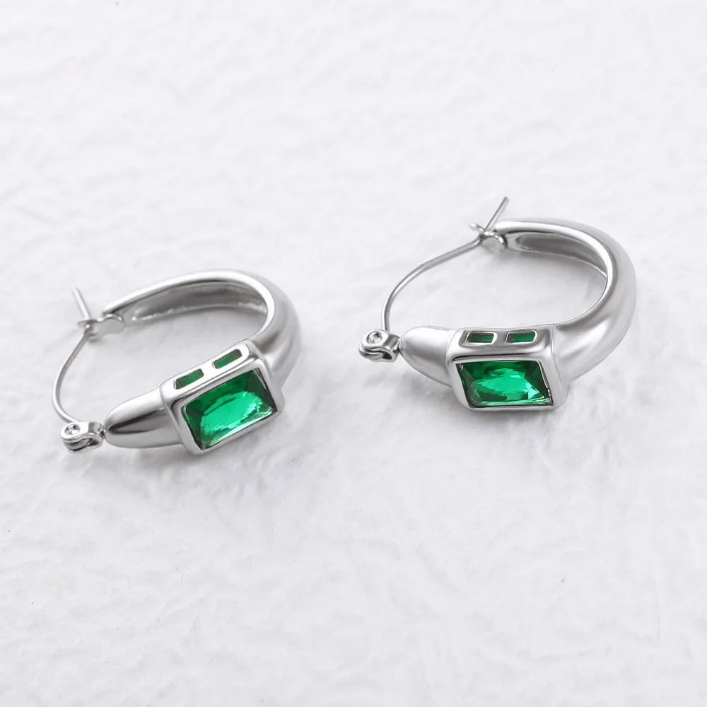 The green crystal hoop earrings in silver-tone stainless steel, on a plain background