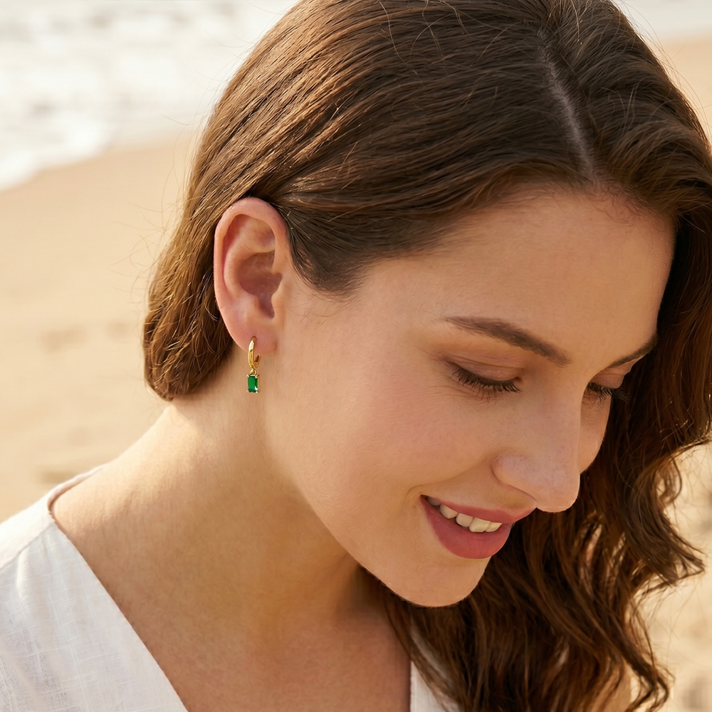 A green crystal hoop earring worn, showing the crystal sitting below the lobe