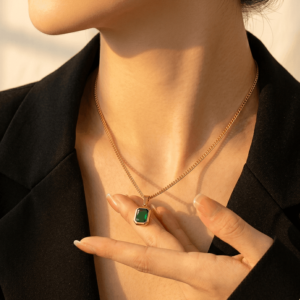 The green crystal pendant worn, sitting just below the collarbone