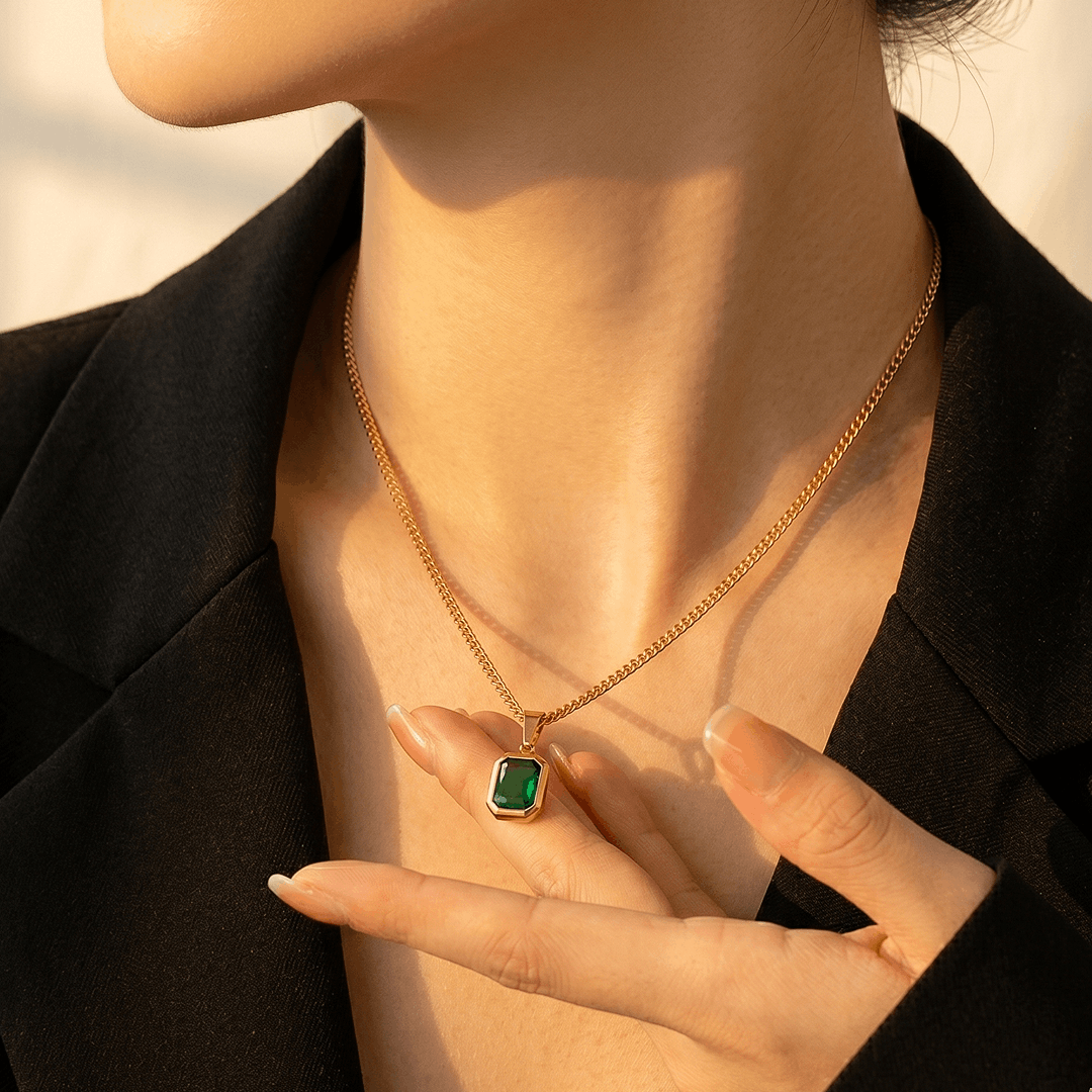 The green crystal pendant worn, sitting just below the collarbone