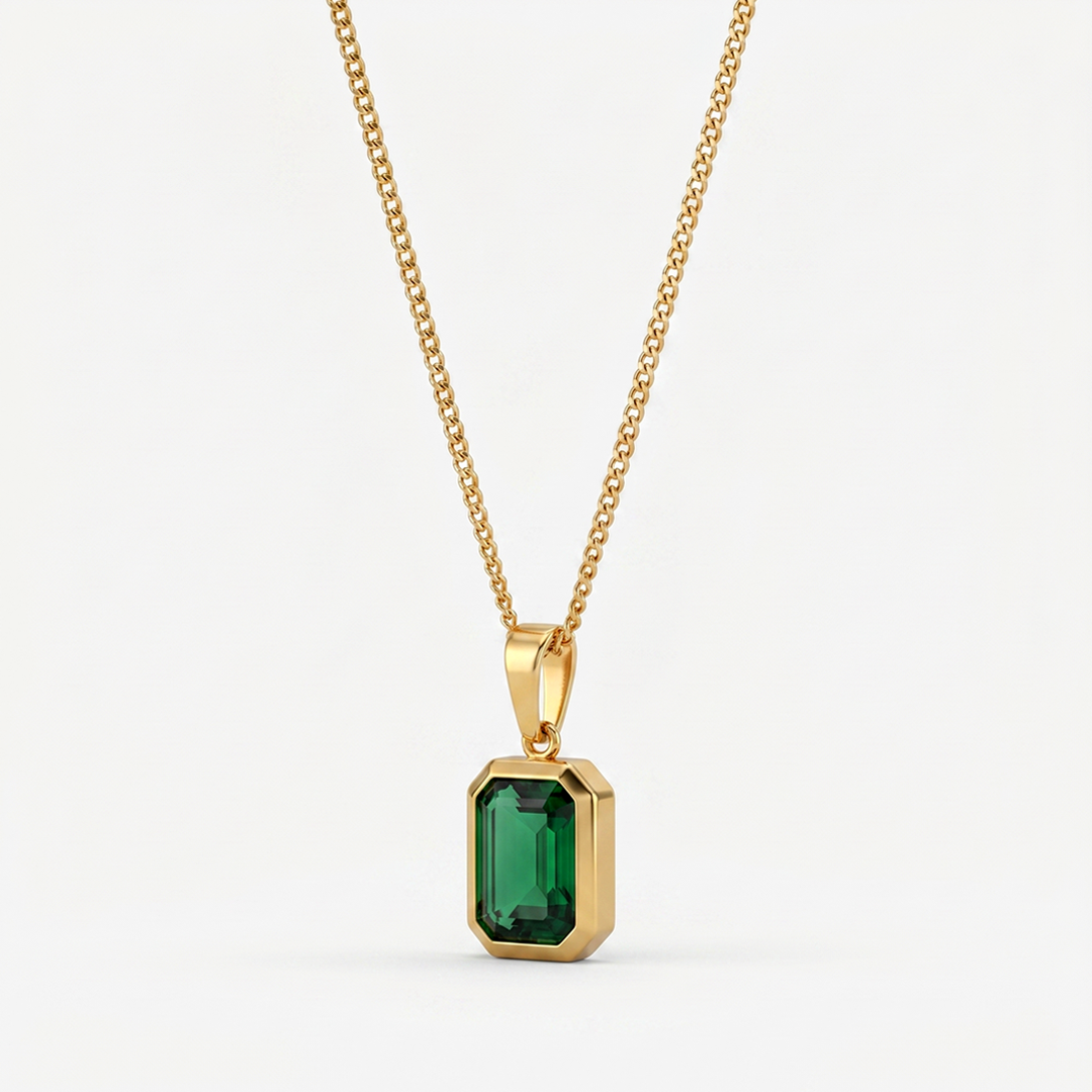 A gold-tone pendant necklace with a rectangular green crystal in a bezel, on a plain background