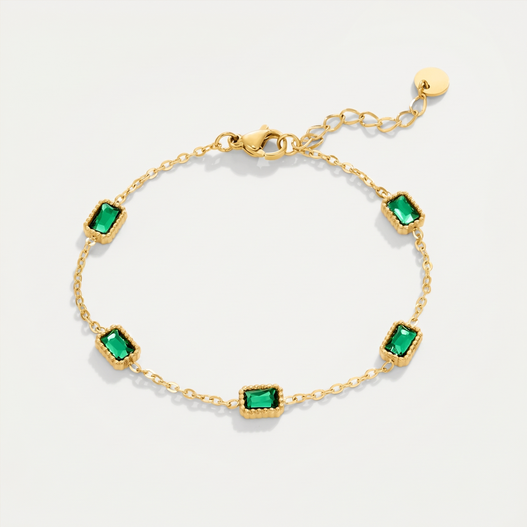 A fine gold-tone chain bracelet with five rectangular green crystals, on a plain background