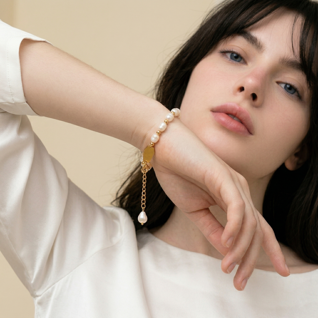 The pearl bracelet worn, seen with the hand raised