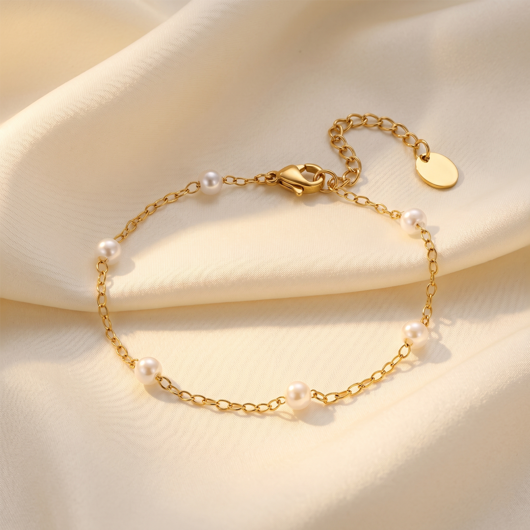 The pearl station bracelet resting on cream silk, showing the clasp and extension