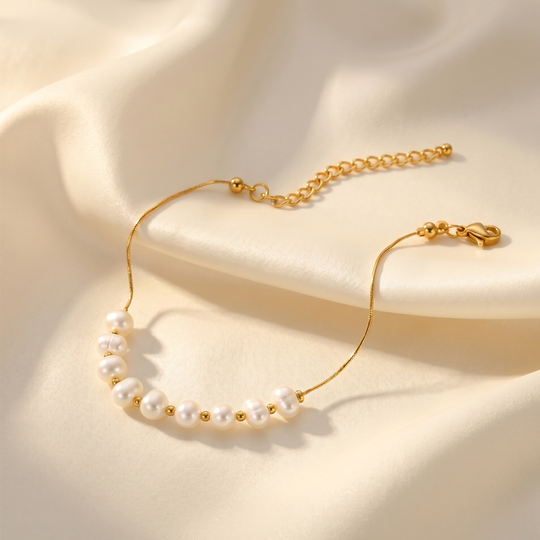 The pearl bracelet resting on cream silk, showing the clasp and extension