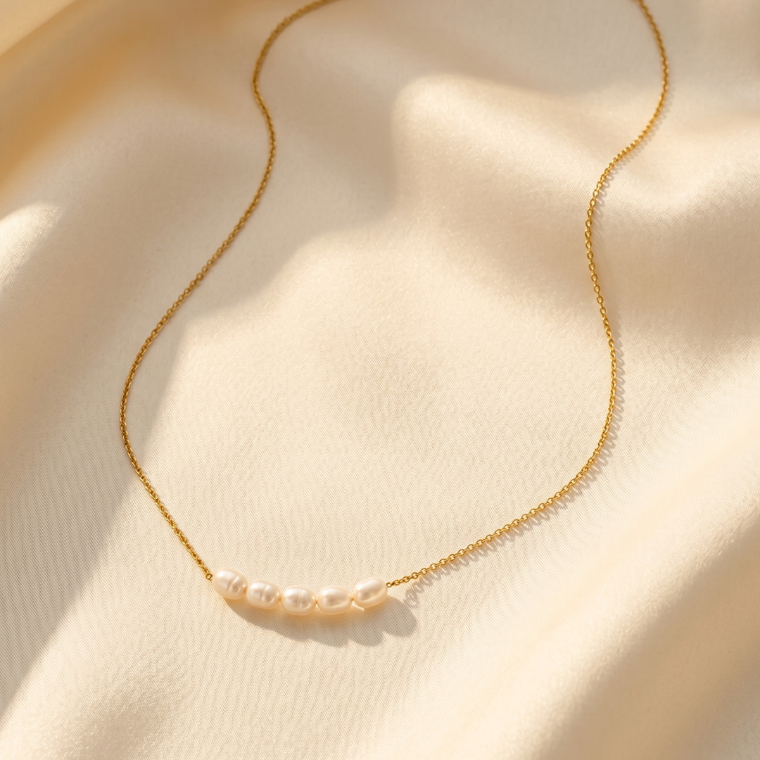 The freshwater pearl necklace resting on cream silk