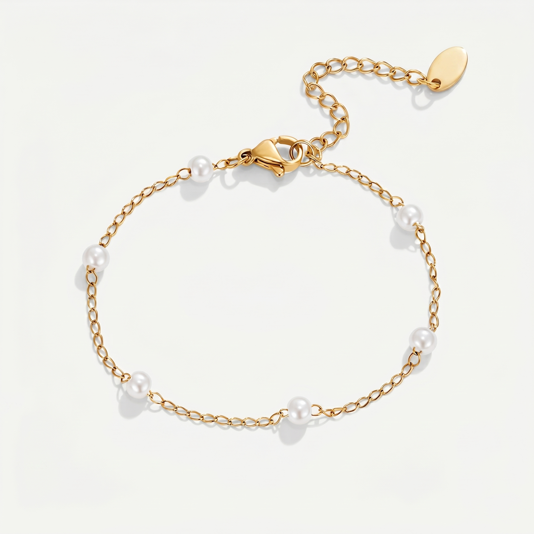 A fine gold-tone chain bracelet with small imitation pearls spaced along it, on a plain background