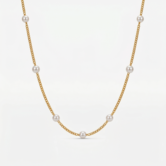 A fine gold-tone chain necklace with small imitation pearls spaced around it, on a plain background