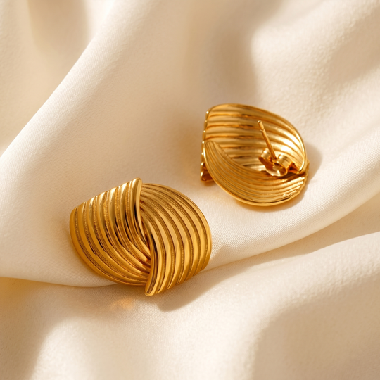 The pair of ribbed studs resting on cream silk