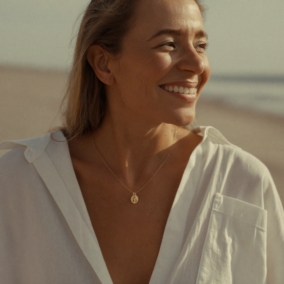A woman in a white linen shirt smiling in warm late-afternoon light on an Australian beach
