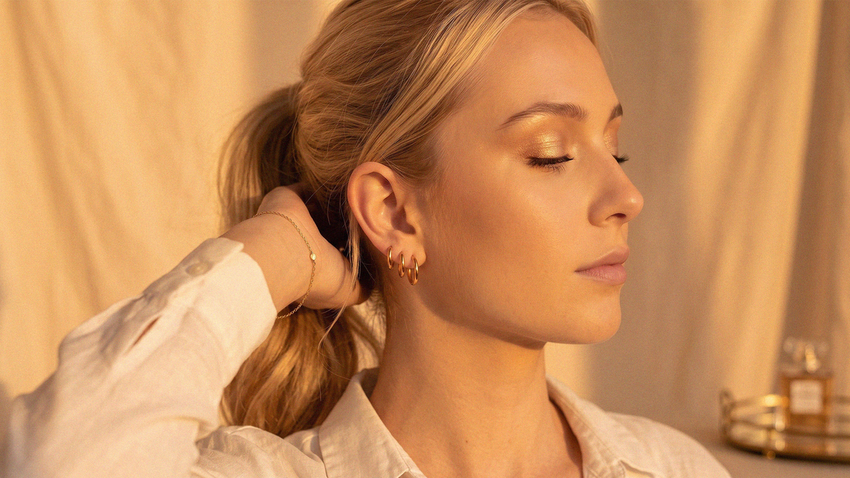 Small gold-tone hoops and a fine chain worn, in warm afternoon light