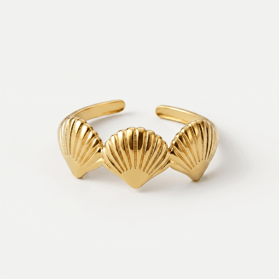 A gold-tone open ring with three ridged scallop shells, on a plain background