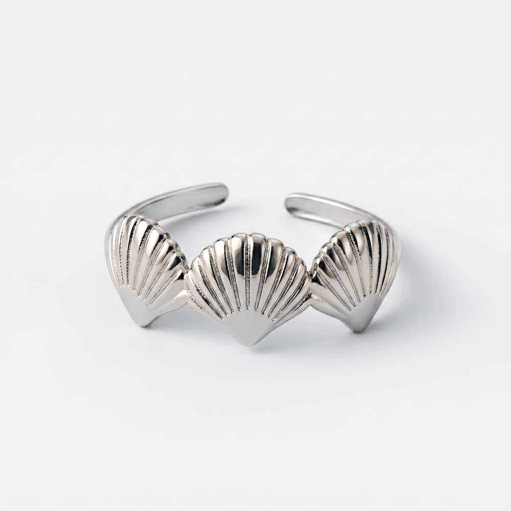 The scallop shell ring in silver-tone stainless steel, on a plain background
