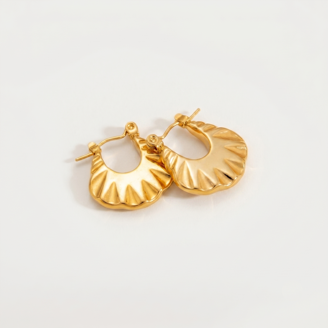 A pair of gold-tone chunky hoops with a scalloped rippled surface, on a plain background