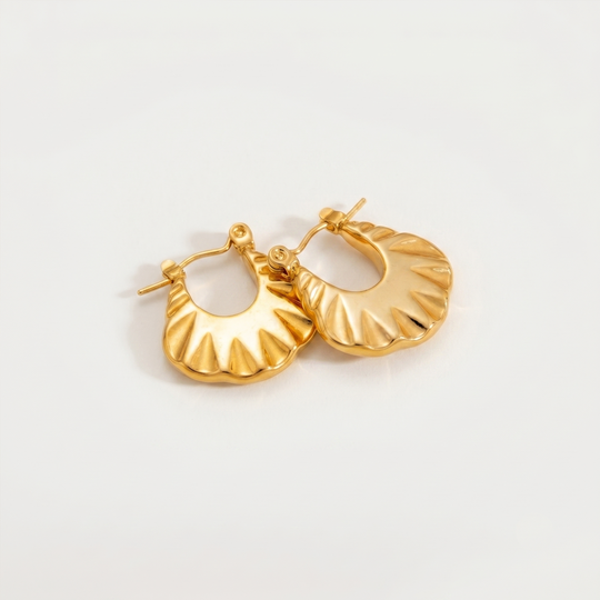 A pair of gold-tone chunky hoops with a scalloped rippled surface, on a plain background
