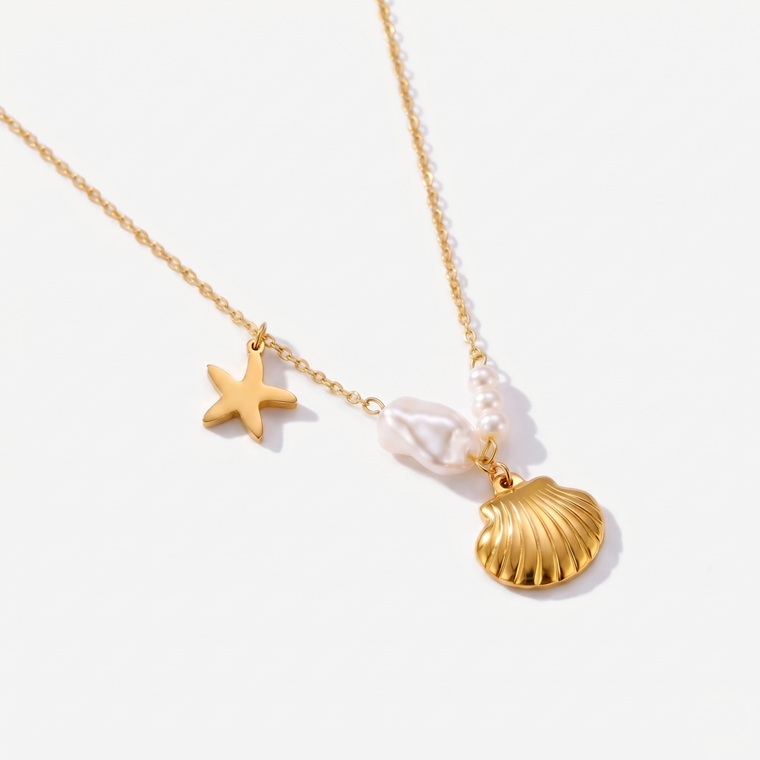 A gold-tone chain necklace with a scallop shell, a starfish and an imitation pearl charm, on a plain background