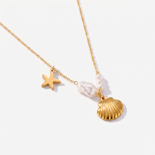 A gold-tone chain necklace with a scallop shell, a starfish and an imitation pearl charm, on a plain background