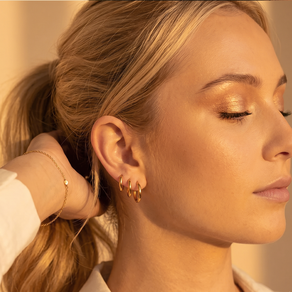 Three sizes of small gold-tone hoops worn stacked up one ear