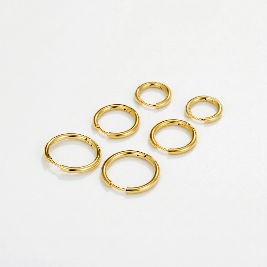 Six small gold-tone hoop earrings in three sizes, laid out on a plain background