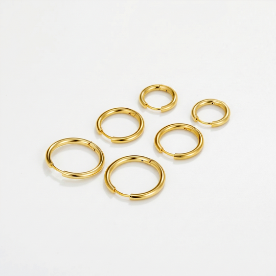 Six small gold-tone hoop earrings in three sizes, laid out on a plain background