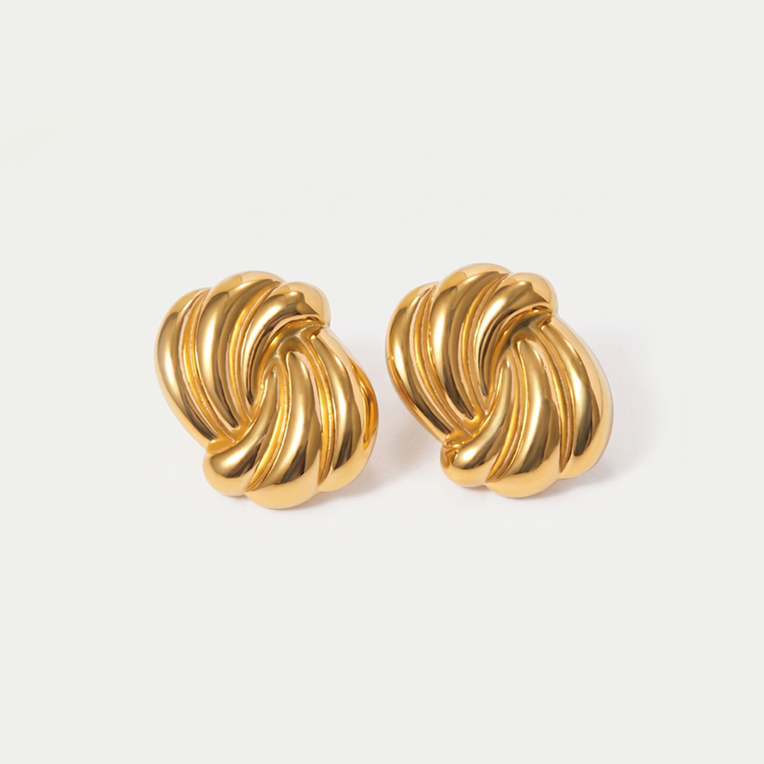 A pair of gold-tone swirl stud earrings on a plain background