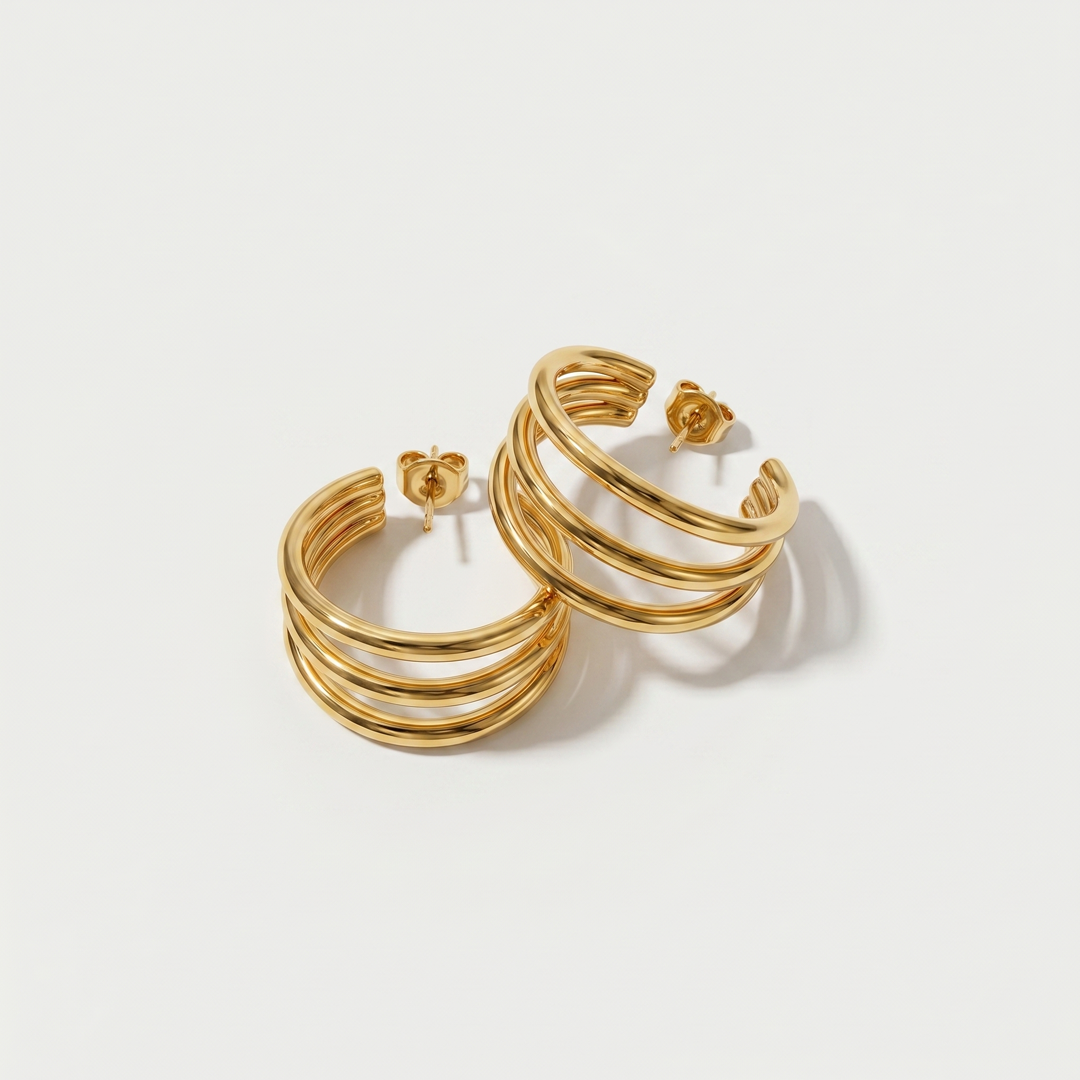 A pair of gold-tone triple hoop earrings, three slim hoops on one post, on a plain background