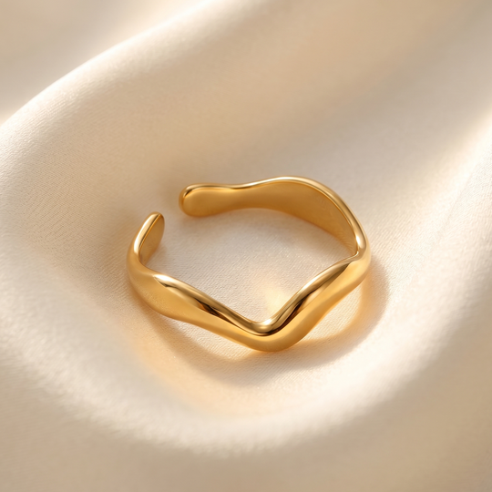 The gold-plated wave ring resting on cream silk
