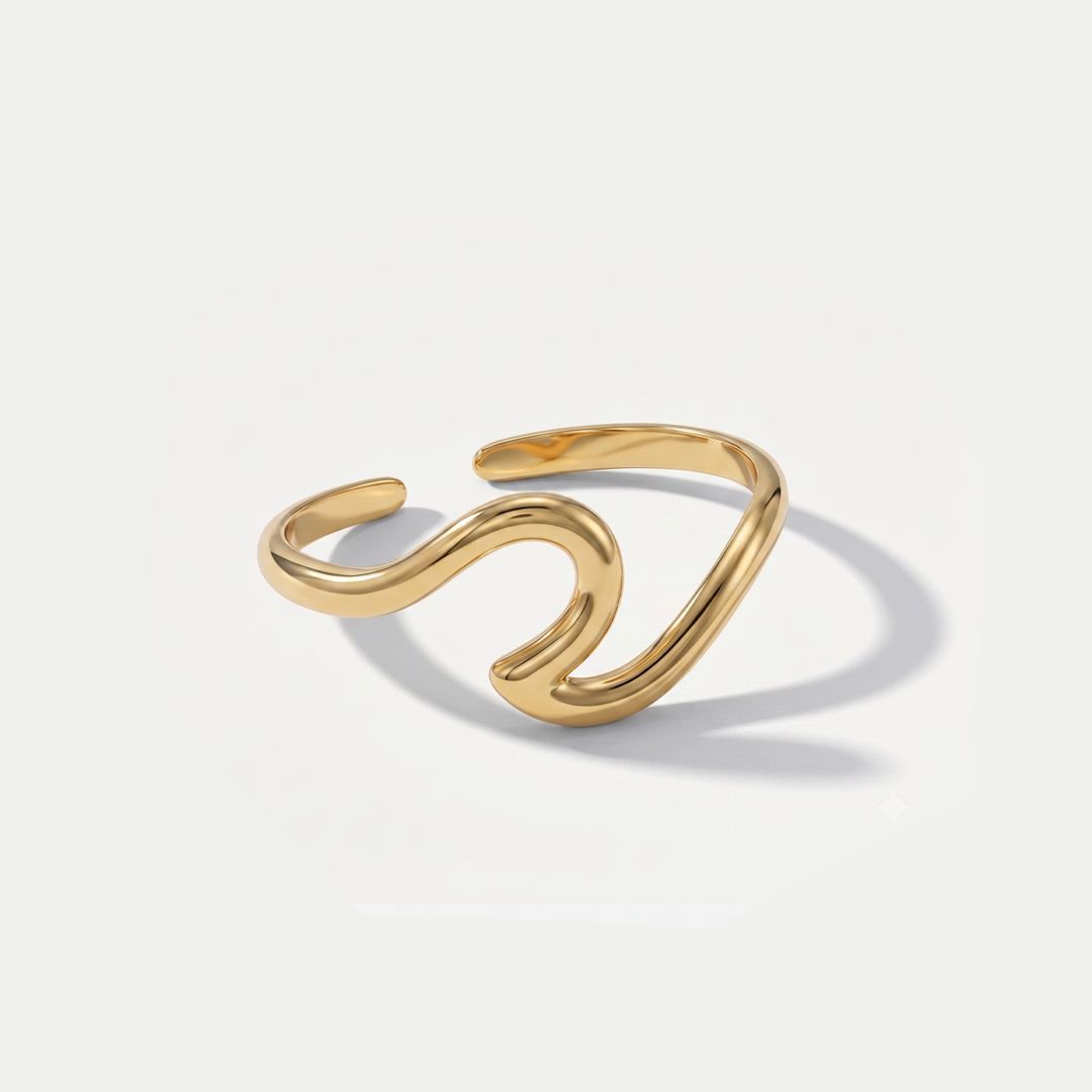 A slim gold-tone open ring shaped like a curling wave, on a plain background