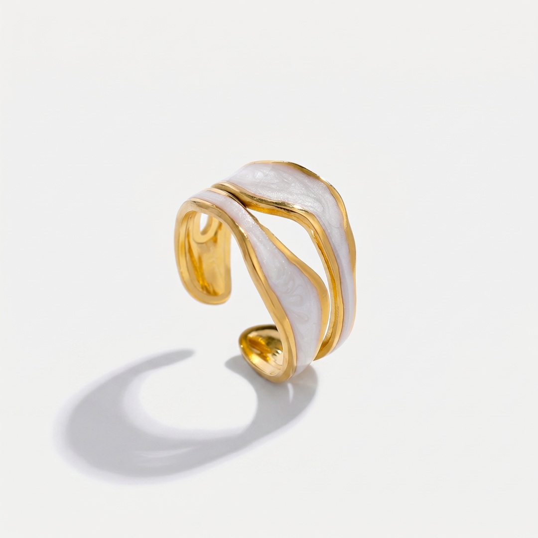 A gold-tone wave wrap ring with a pearlescent white inlay, on a plain background