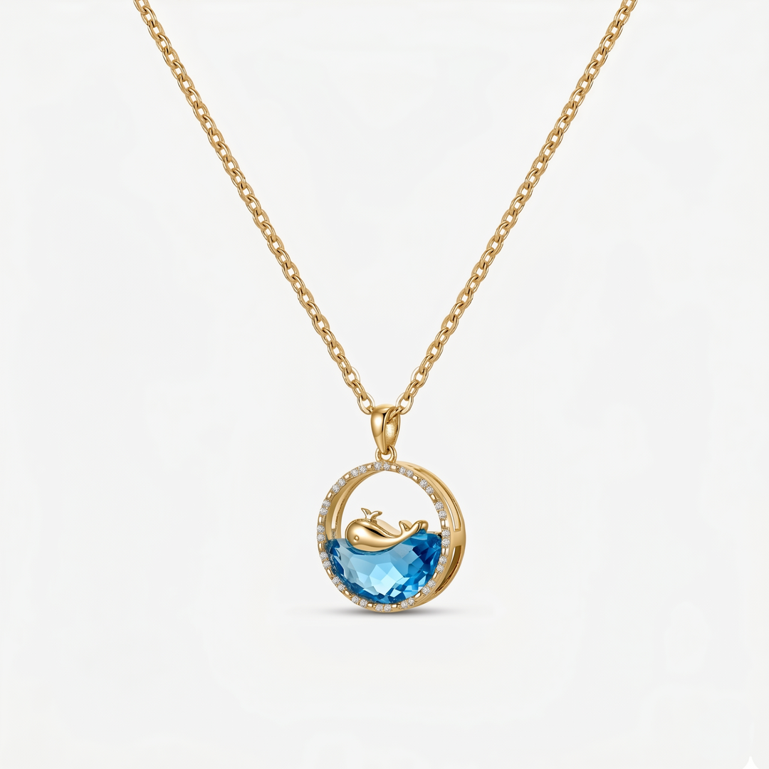 A gold-tone pendant necklace with a whale motif on a faceted blue inlay, on a plain background